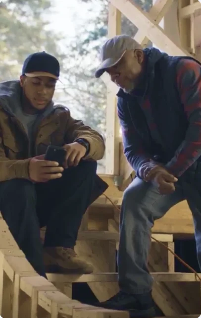 Two contractors checking a phone on a job site