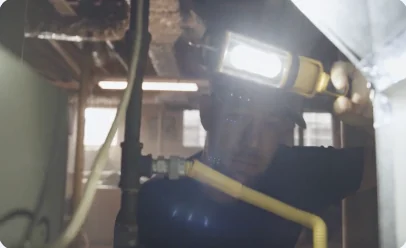 Technician working on basement piping with a headlamp